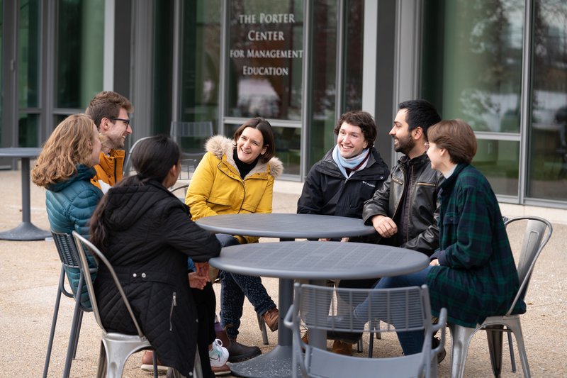 Professor Duflo sitting at tables with six students